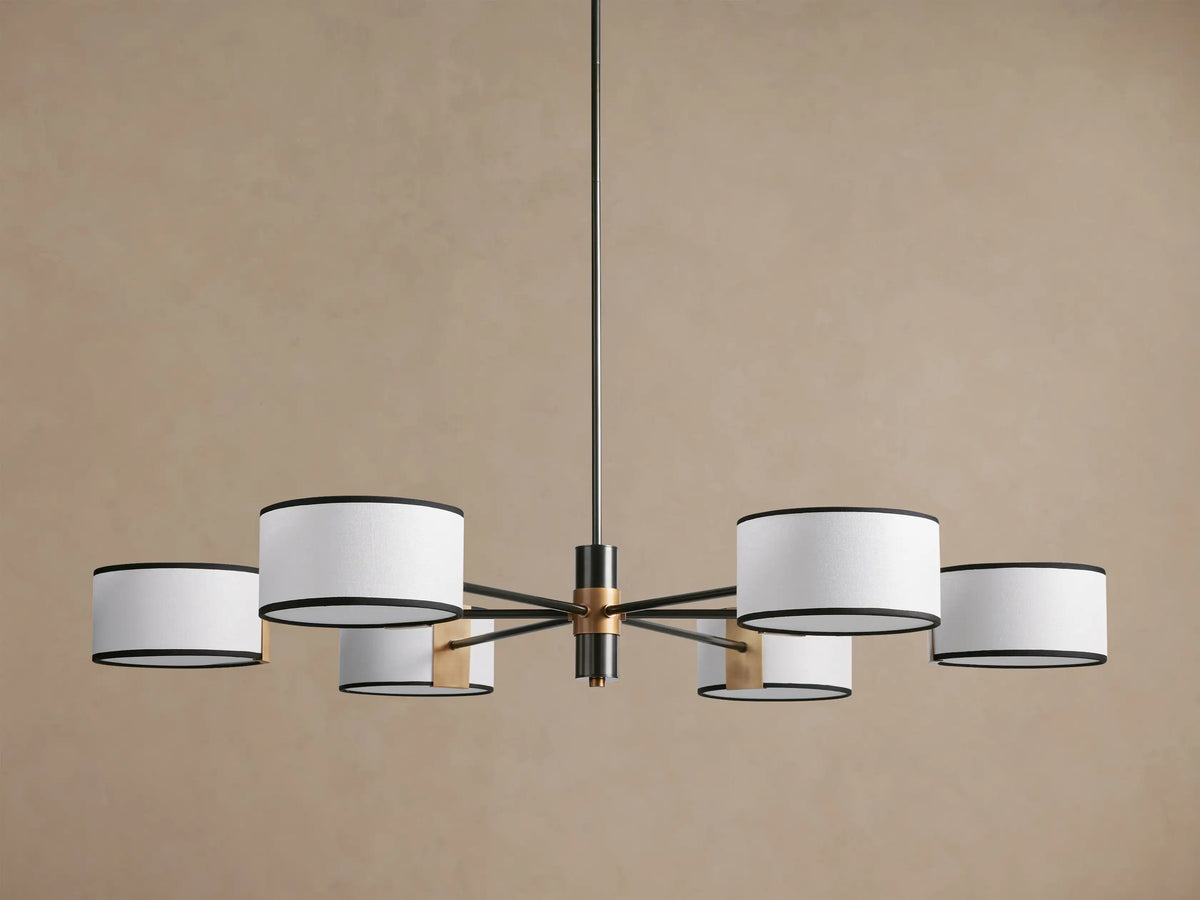 Daphne Fabric Round Chandelier with 6 white linen shades and black trim, dark bronze arms, hanging against a brown wall.