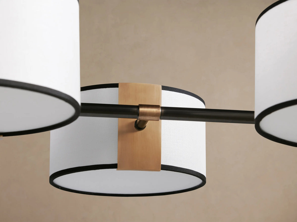 Daphne Fabric Linear Chandelier: 6 white linen shades with black trim, bronze frame, suspended from above.