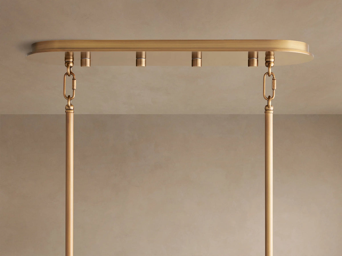 Close-up of Delsie Oval Chandelier's burnished brass oval ceiling canopy, with two hanging rods suspended by chain links.
