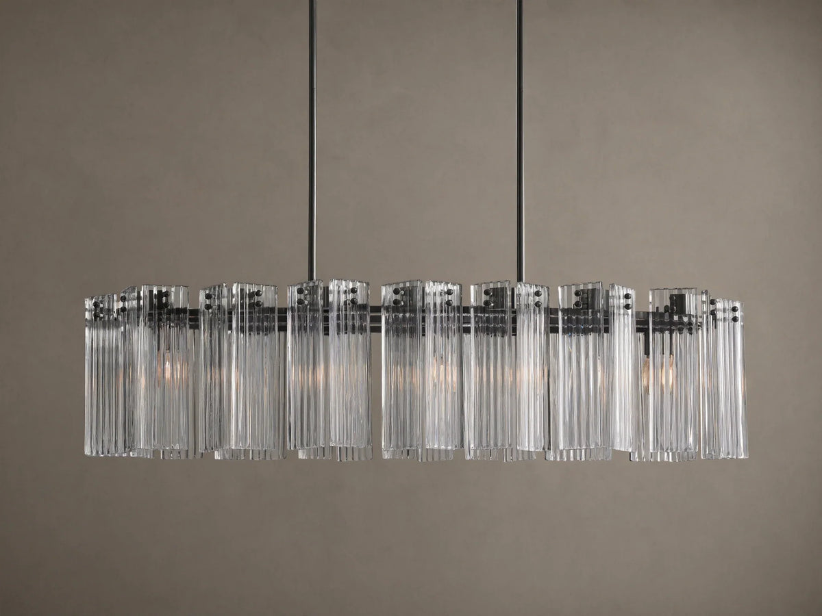 Delsie Oval Chandelier: clear ribbed glass cylinders hang from a dark oval frame, suspended by two rods against a wall.