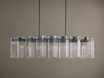 Delsie Oval Chandelier: clear ribbed glass cylinders hang from a dark oval frame, suspended by two rods against a wall.