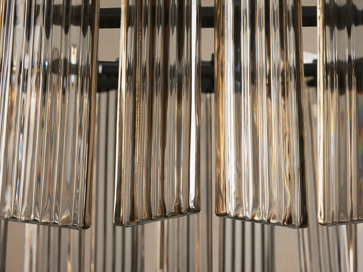 Delsie Oval Chandelier close-up: vertical ribbed glass panels in champagne tones, shimmering, with dark structural elements.