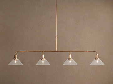 Theron Linear Chandelier: horizontal brass bar, 4 lit bulbs inside milk glass cone shades, hanging against brown wall.