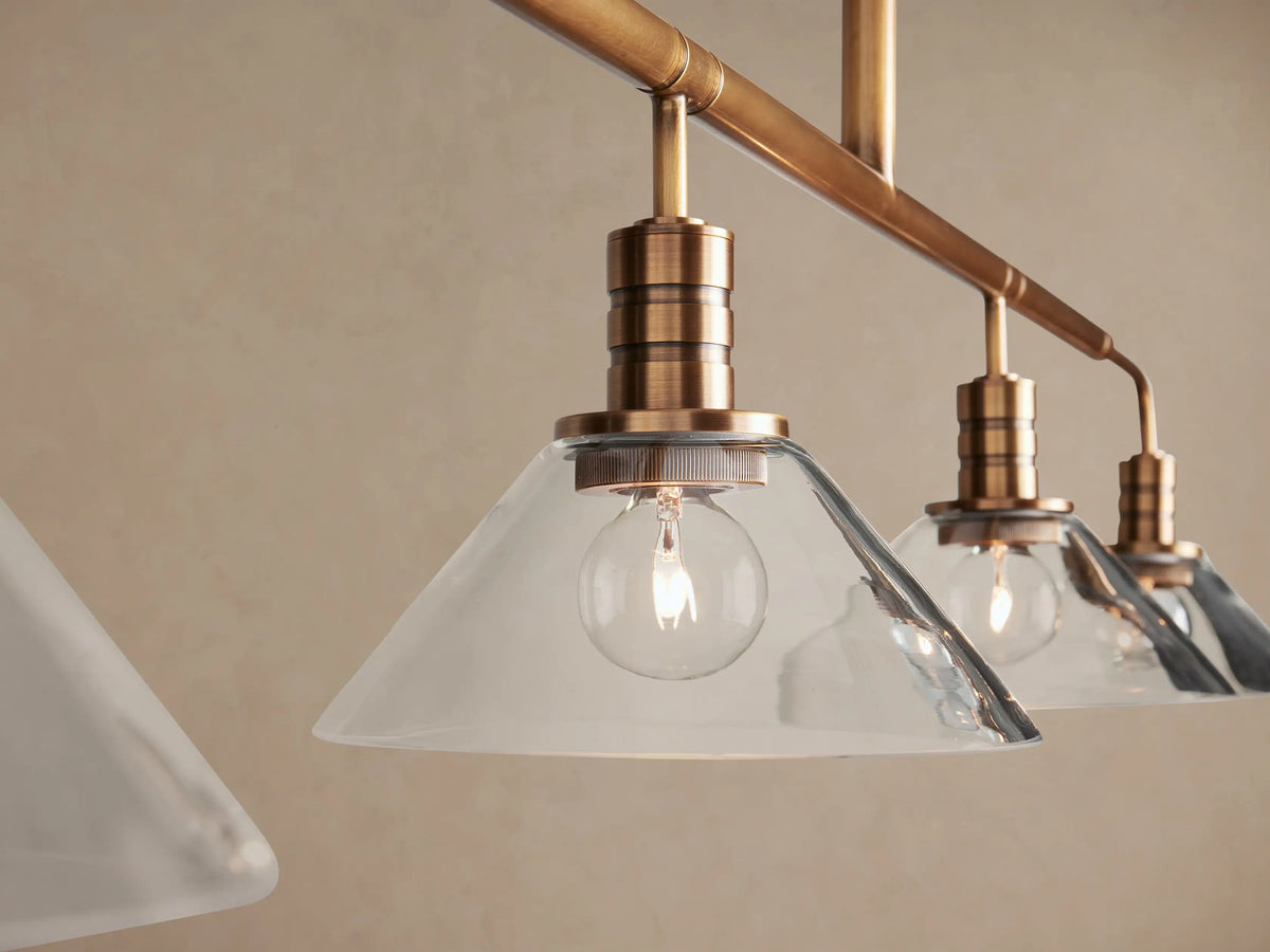 Theron Linear Chandelier, brass finish, 4 clear cone-shaped glass shades on a horizontal rod, suspended by a vertical rod.