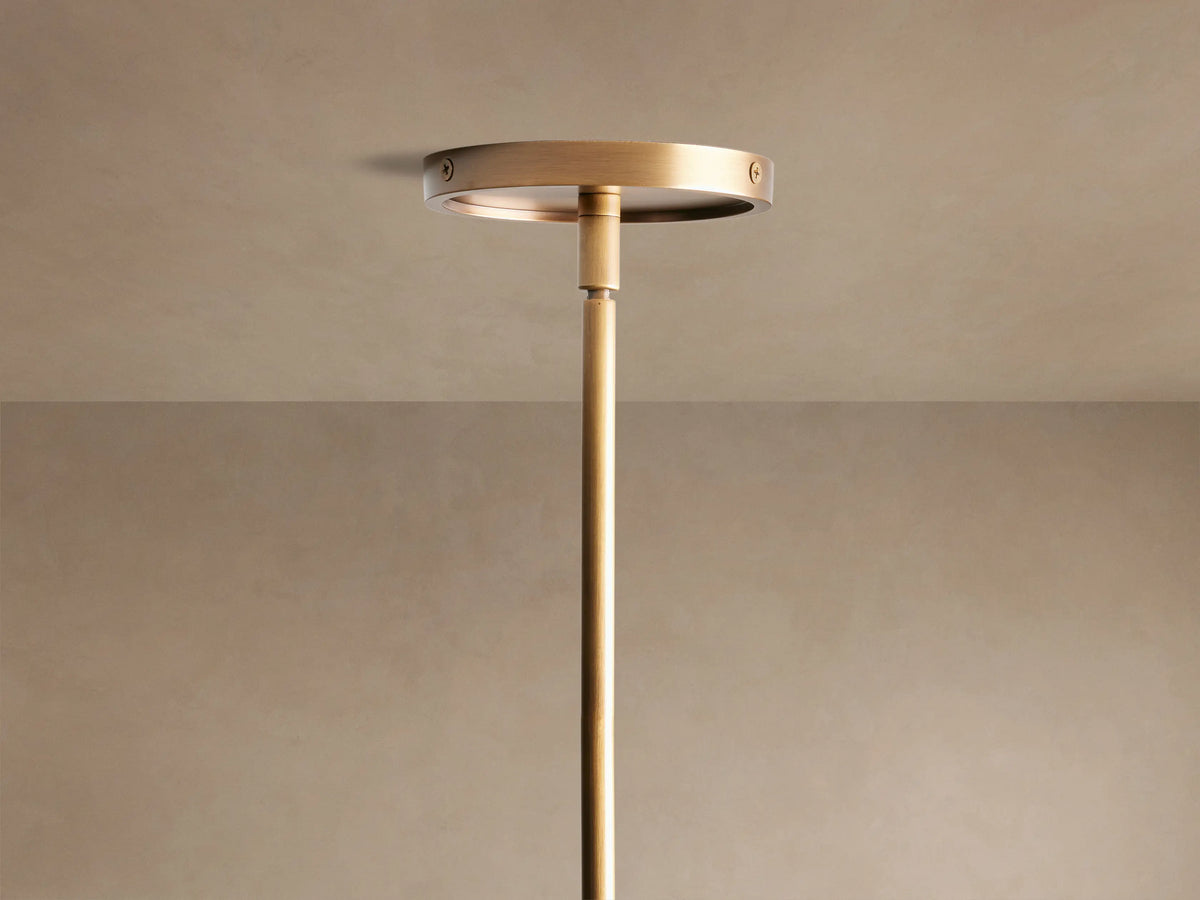 Close-up of Theron Linear Chandelier with a brass bar suspending three illuminated frosted glass cones, fourth partially visible.