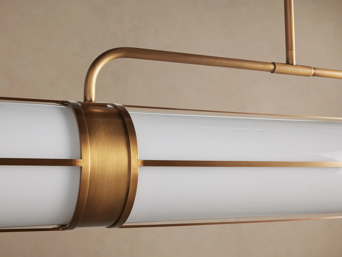 Remming Linear Chandelier: two white milk glass cylindrical shades with burnished brass frame, suspended from a brass rod.