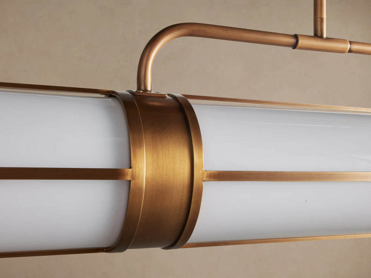 Remming Linear Chandelier with a horizontal burnished brass frame and two white milk glass cylinders, suspended from two rods.