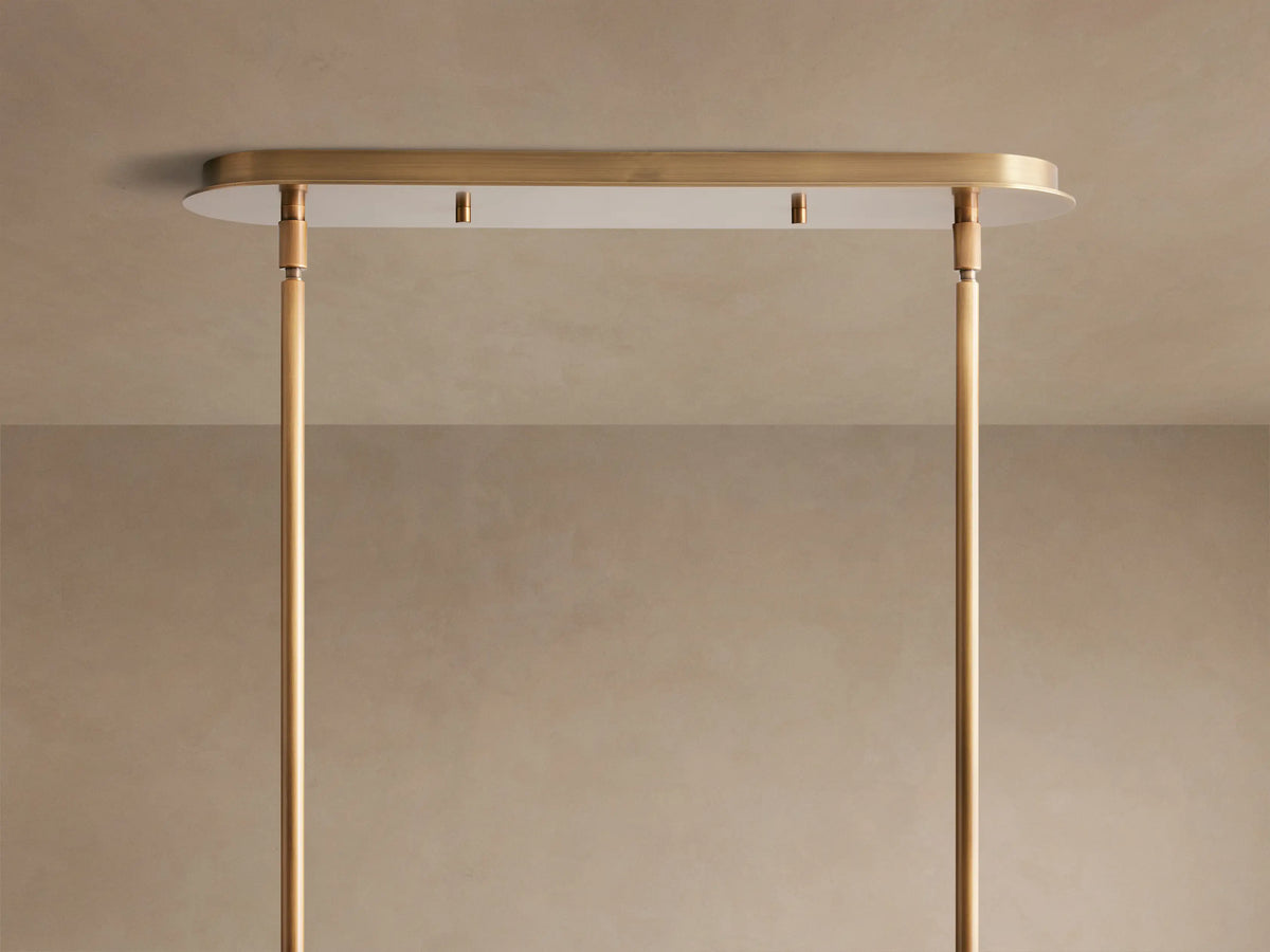 Close-up of a Remming Linear Chandelier, showing its long milk glass cylinder encased in burnished brass details and suspension arm.