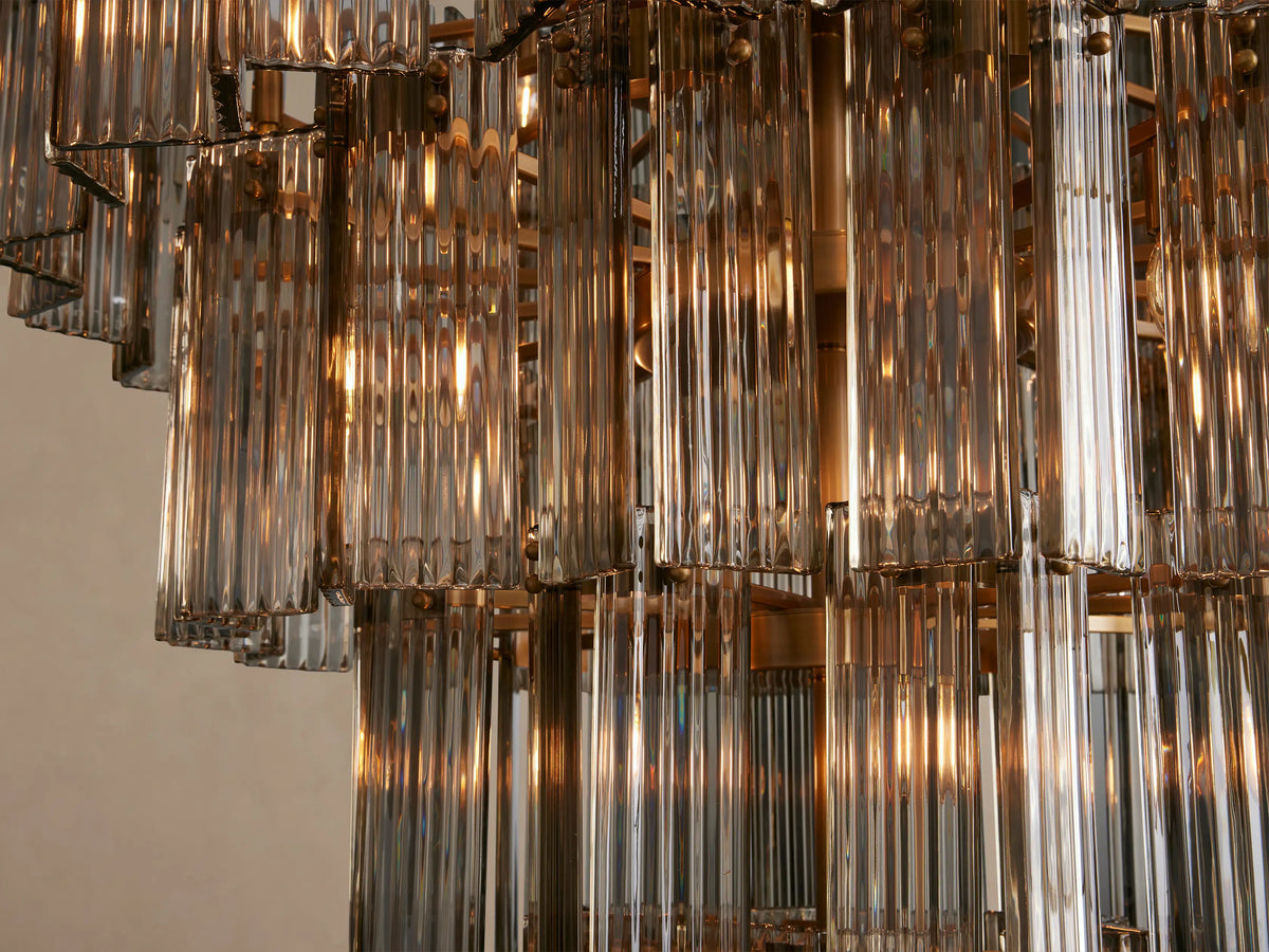 Delsie Round Chandelier, tiered with many vertical, clear ribbed glass rods and burnished brass frame, hanging vertically.