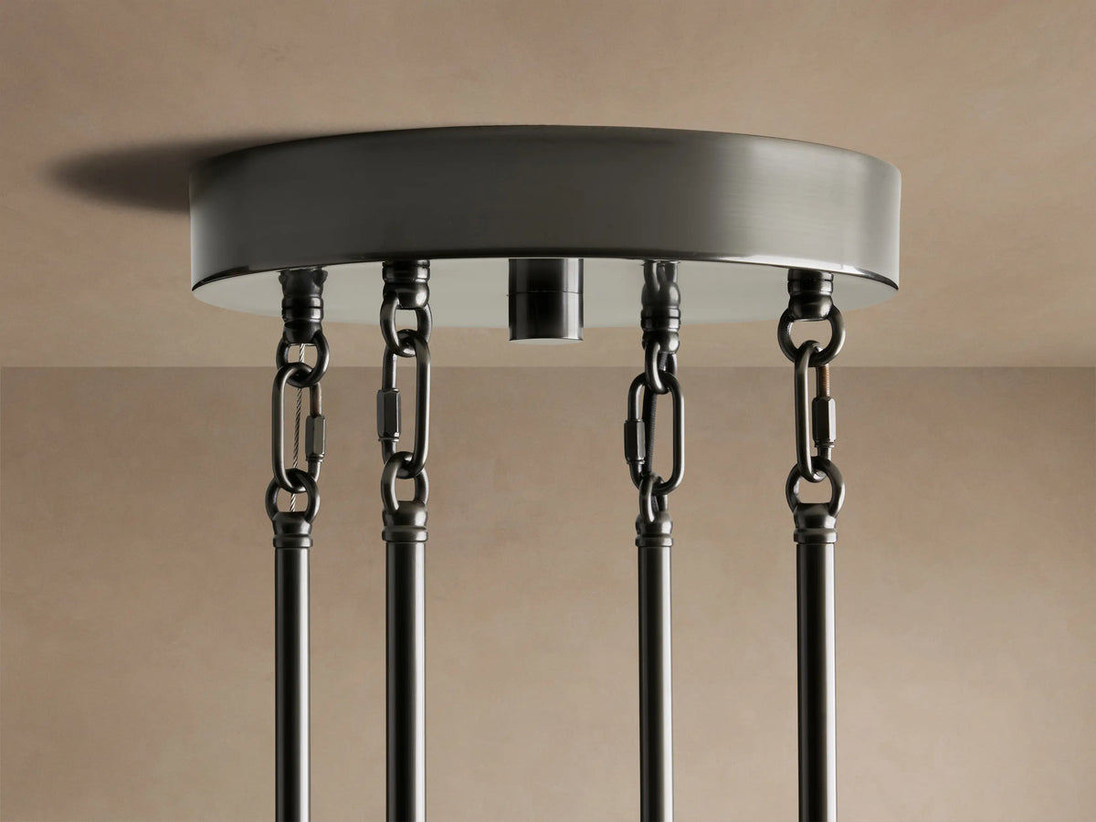 Close-up of Delsie Round Chandelier with clear fluted glass panels glowing with warm light on a dark bronze metal frame.