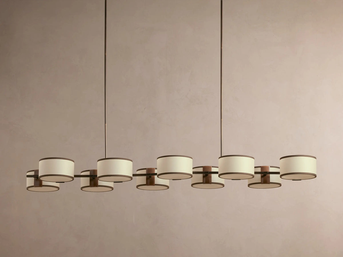 Eleven round hanging pendant lights with warm amber glow against a beige background, suspended in a linear arrangement.