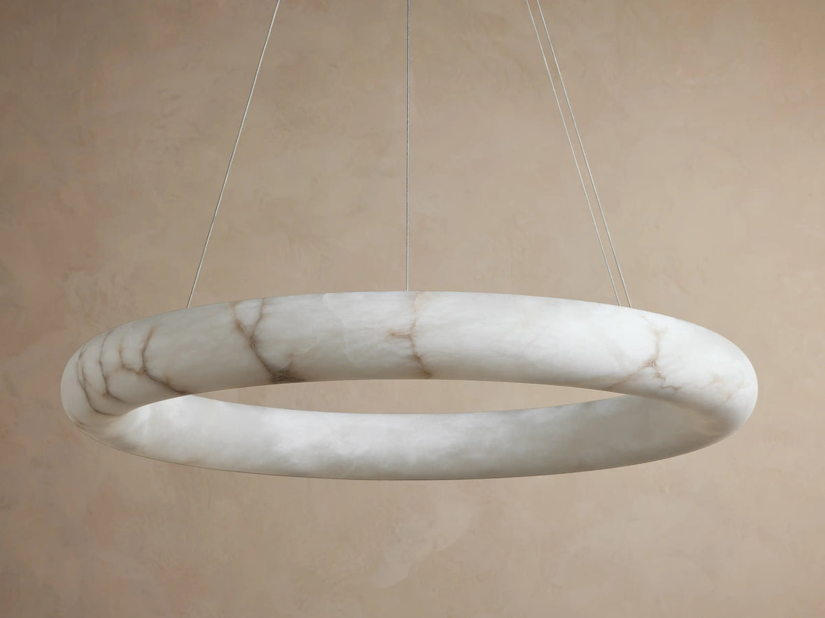 Halima Halo Chandelier with a glowing alabaster stone ring, suspended by steel cables against a neutral background.