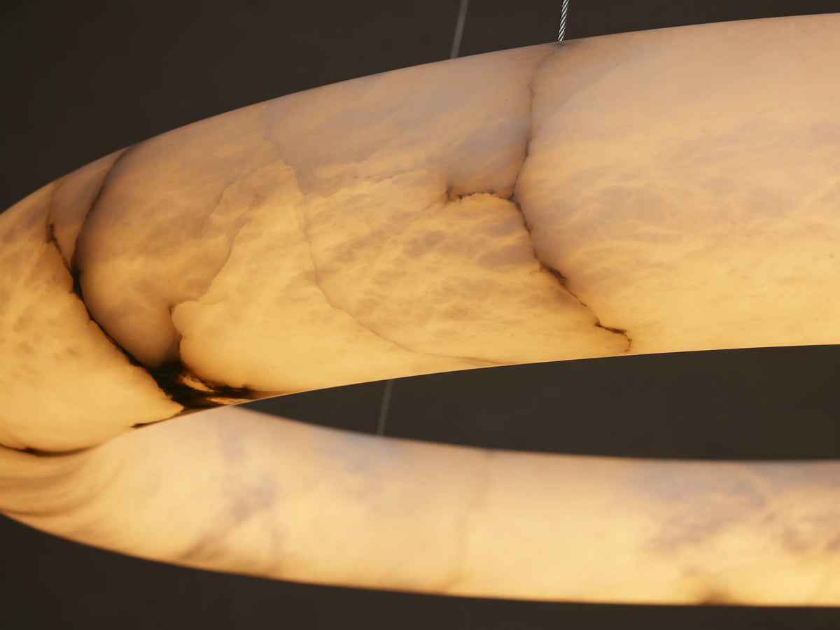 Halima Halo Chandelier made of Spanish alabaster, featuring a circular design with subtle veining, suspended by thin steel cables.