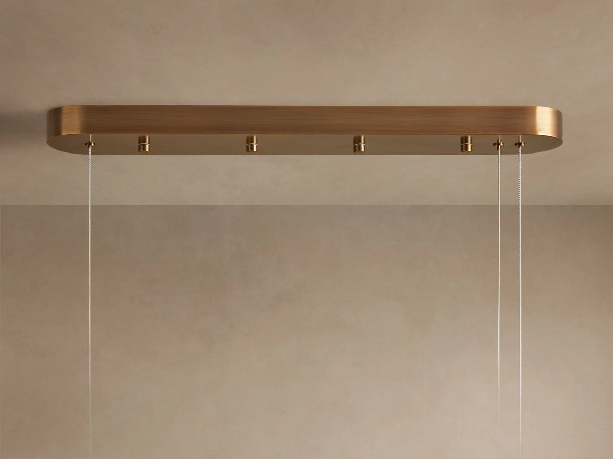 Halima Linear Chandelier with a glowing alabaster stone finish, suspended by steel cables, creating a warm ambiance.