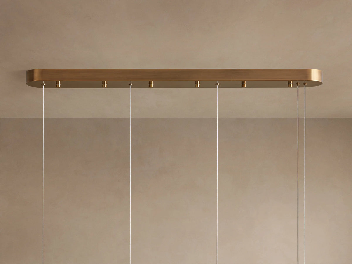 Halima Linear Chandelier with glowing alabaster stone tube, mounted by two steel cables against a neutral background.