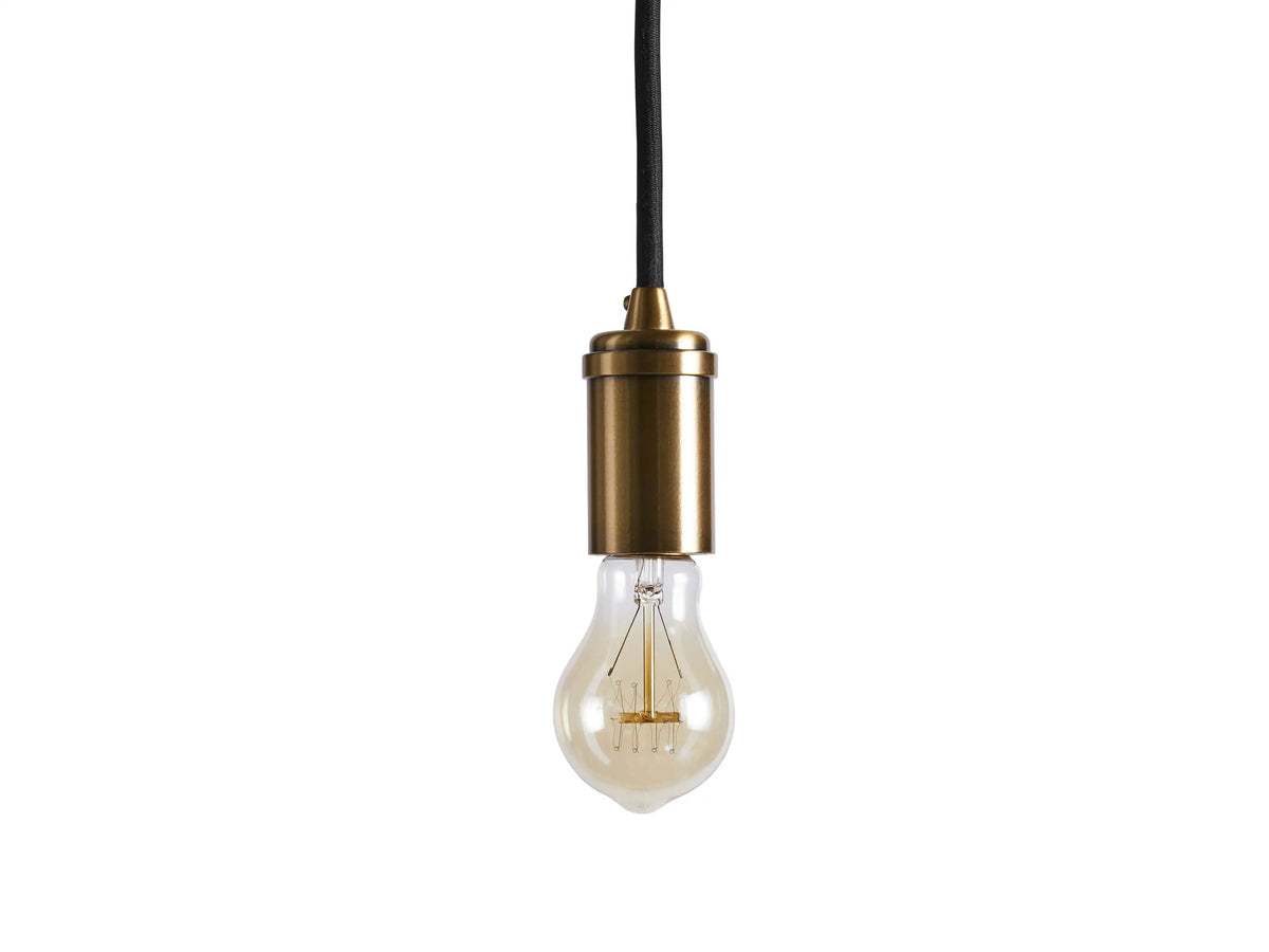 The Ohlson Brass Swag Pendant features a brass-plated socket with an exposed lightbulb, hanging by a black fabric-wrapped cord.