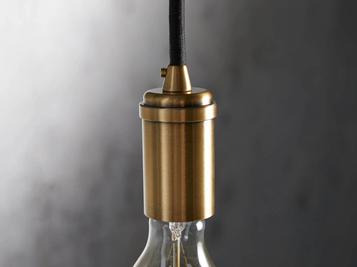 Ohlson Brass Swag Pendant with a brass-plated finish, E26 bulb holder, transparent bulb, and black fabric cord.