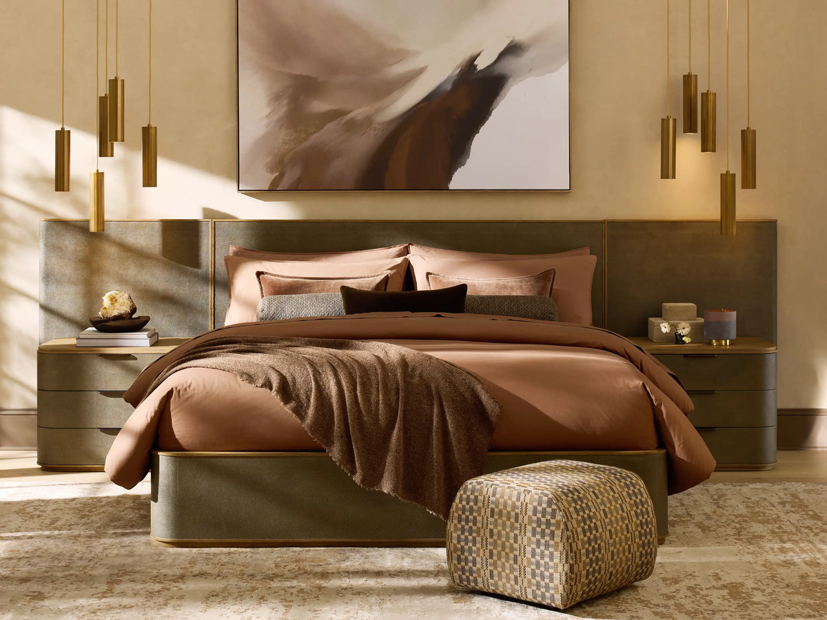 Five bronze cylindrical pendant lights hanging in a staggered arrangement against a textured beige wall.
