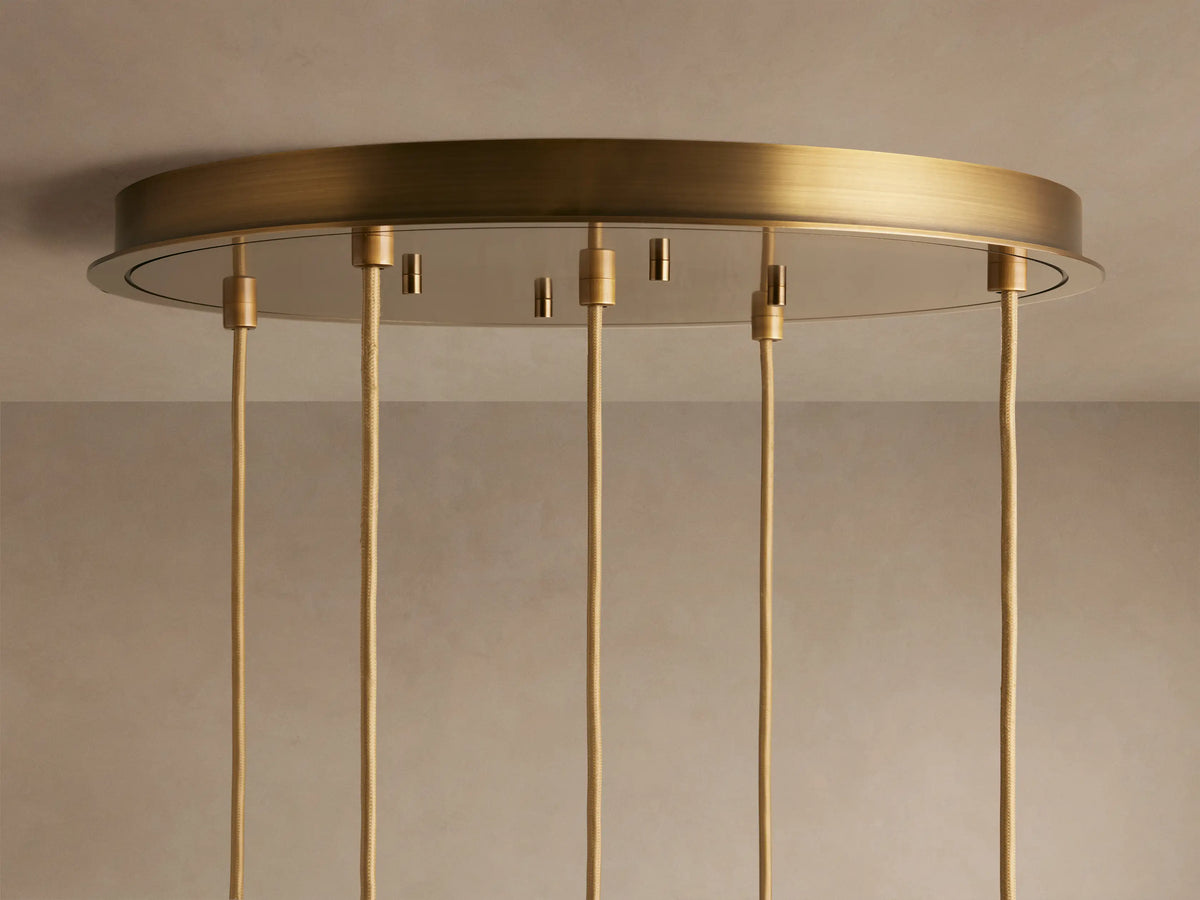 Ceiling light fixture with a round, brushed brass base and multiple hanging cords. The fixture is mounted on a light-colored ceiling.