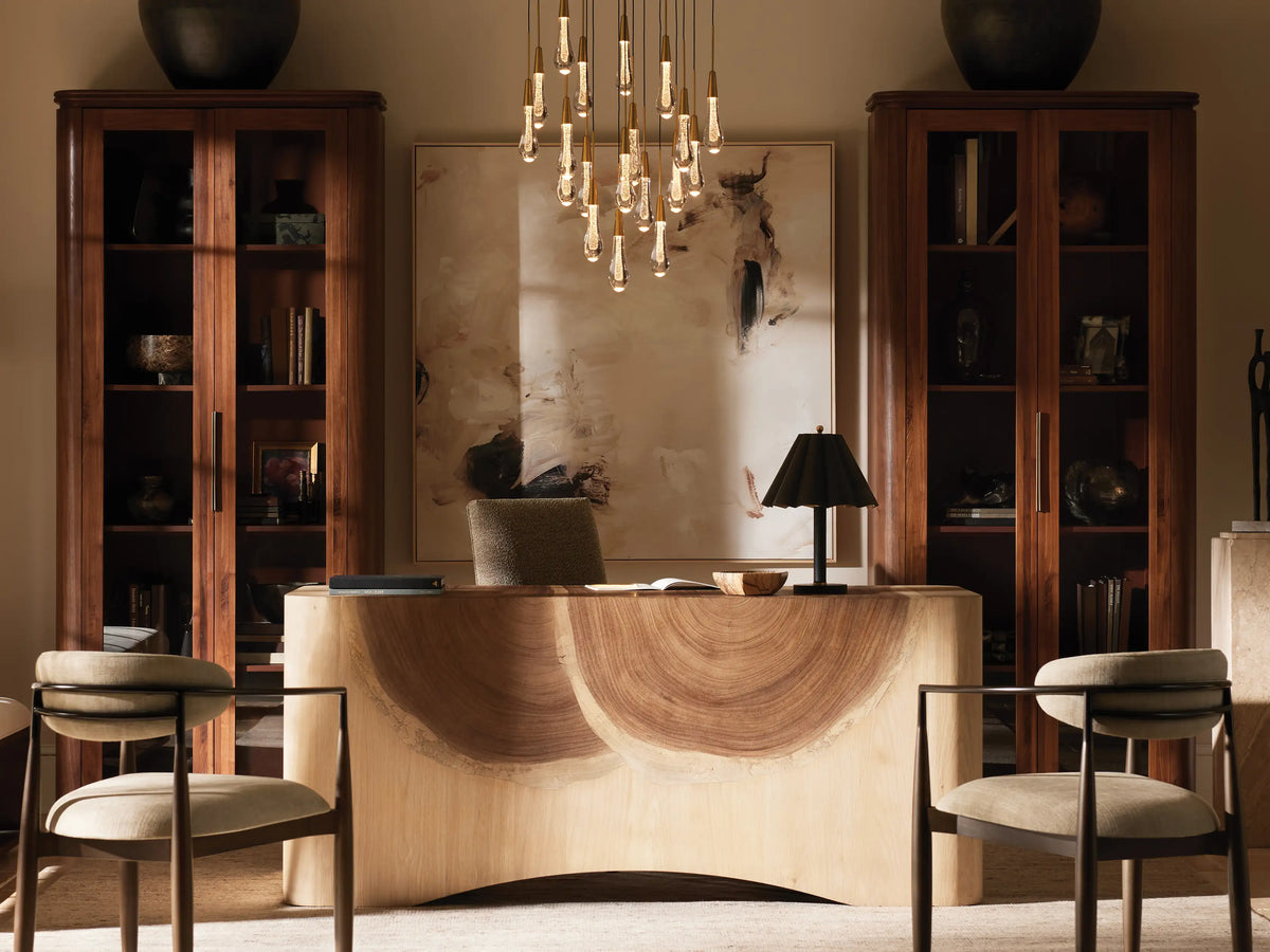 Soltaire Round Chandelier with multiple teardrop-shaped glass pendants, each with brass caps, suspended from long cords against a neutral wall.