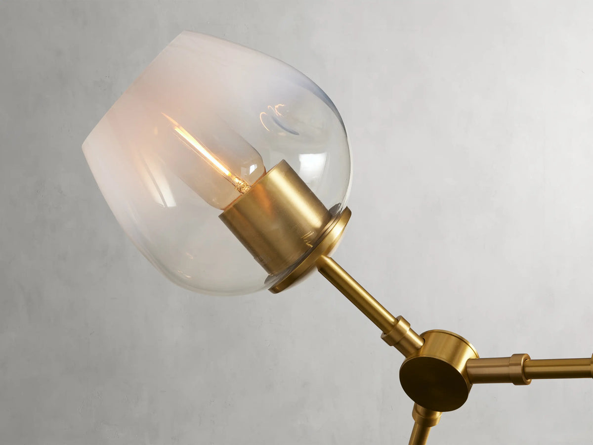 Noella Brass Chandelier with five branches, matte brass finish, clear glass globes on a steel frame, against a light grey background.
