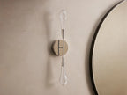 Soltaire Double Sconce mounted on a wall, features two teardrop LED bulbs on a polished nickel backplate, emitting warm light.