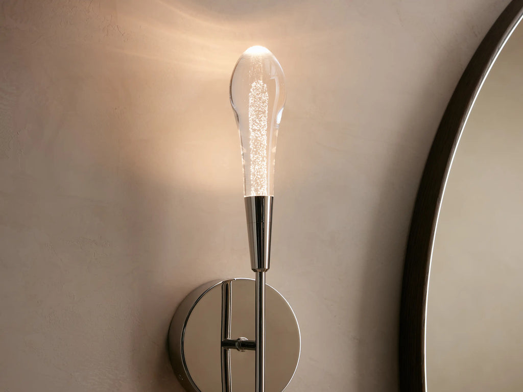Soltaire Double Sconce with a nickel finish on a round backplate, featuring two elongated clear glass shades extending vertically.