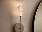 Soltaire Double Sconce with a nickel finish on a round backplate, featuring two elongated clear glass shades extending vertically.