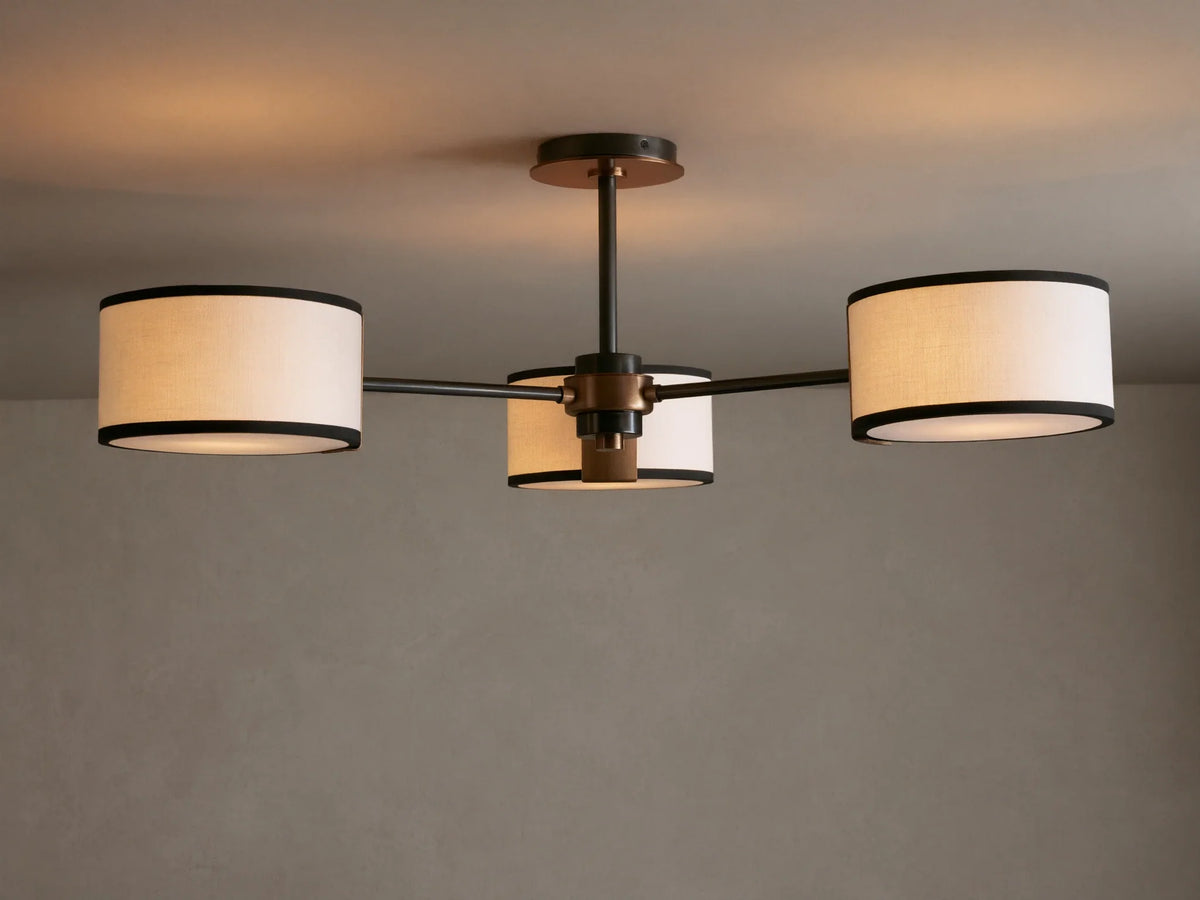 Daphne Flush Mount: 3 white linen shades with black trim, dark bronze frame, lit against a grey ceiling.