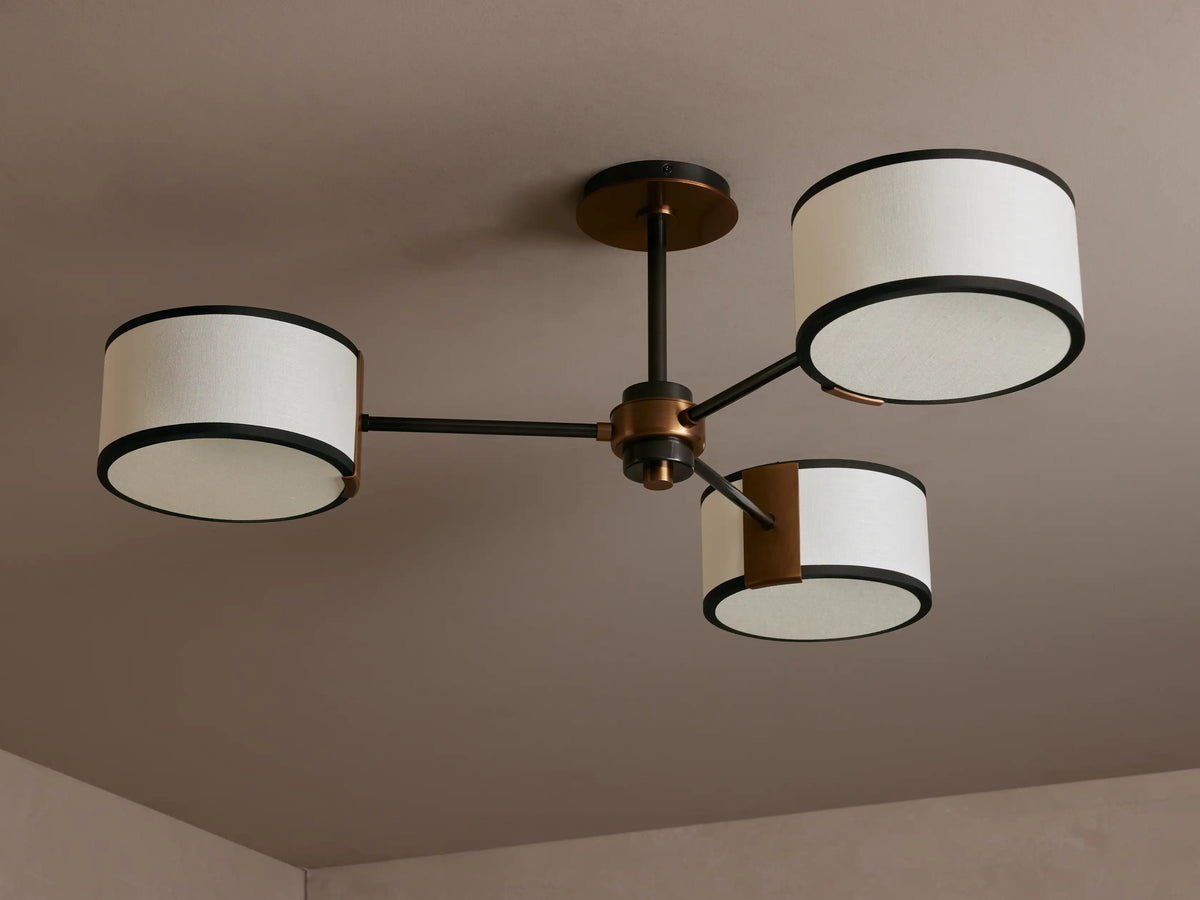 Daphne Fabric Flush Mount light fixture: three white linen shades with black trim, bronze arms, mounted on ceiling, glowing.