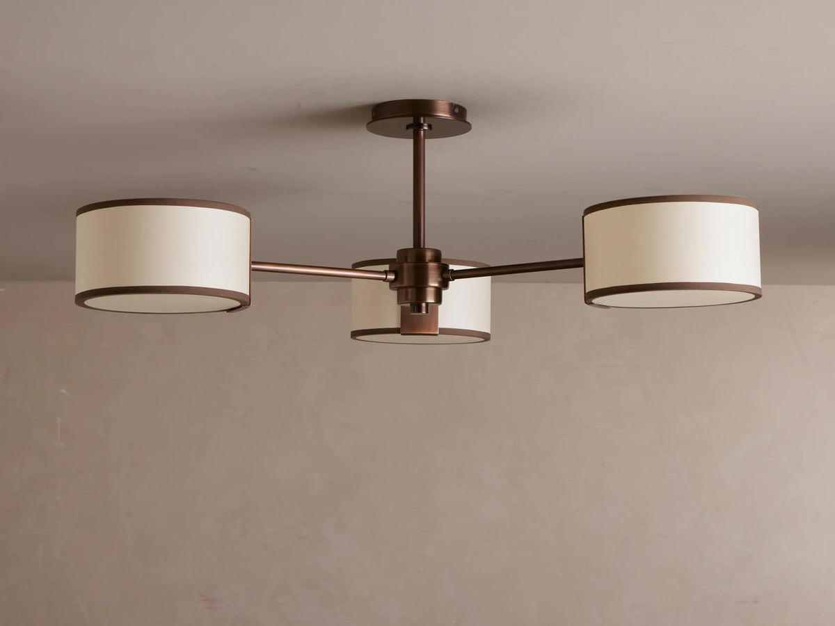 Daphne Fabric Flush Mount with three glowing creamy fabric shades & dark bronze accents, mounted on a ceiling.