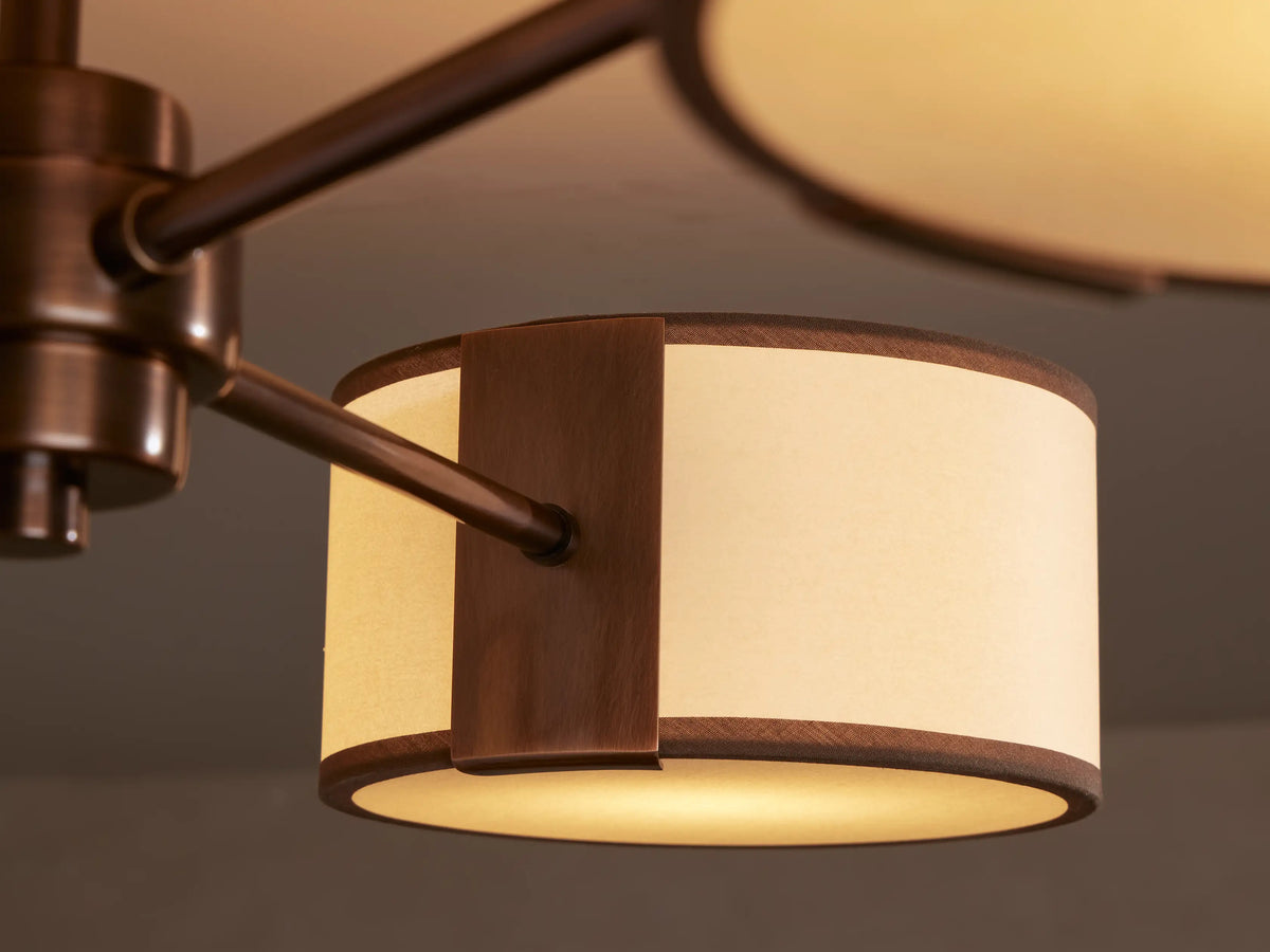 Daphne Flush Mount: Bronze ceiling fixture with three arms, each holding an off-white fabric shade with brown trim.