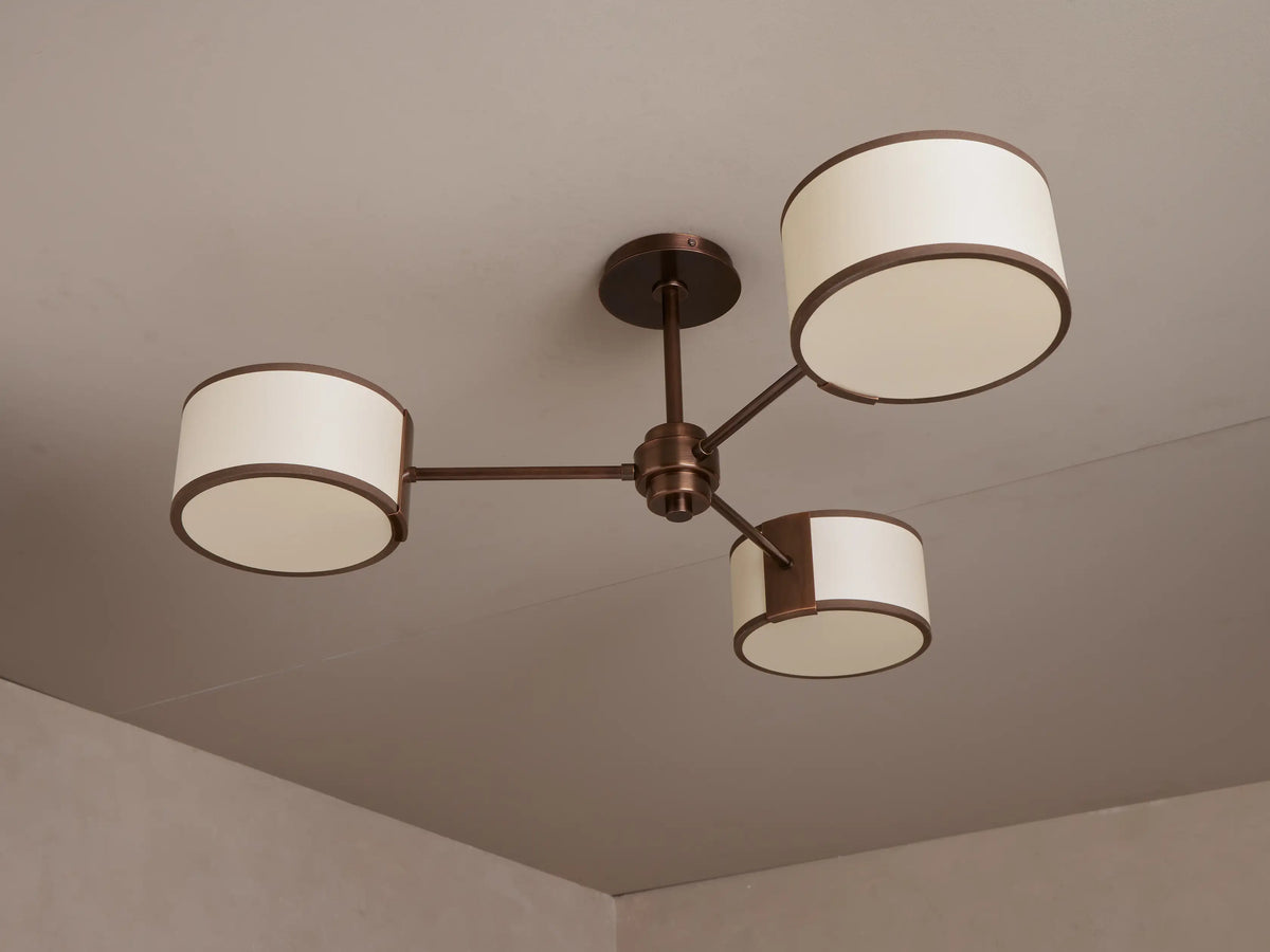 Daphne Fabric Flush Mount: Bronze 3-arm ceiling light with three lit cylindrical cream fabric shades.