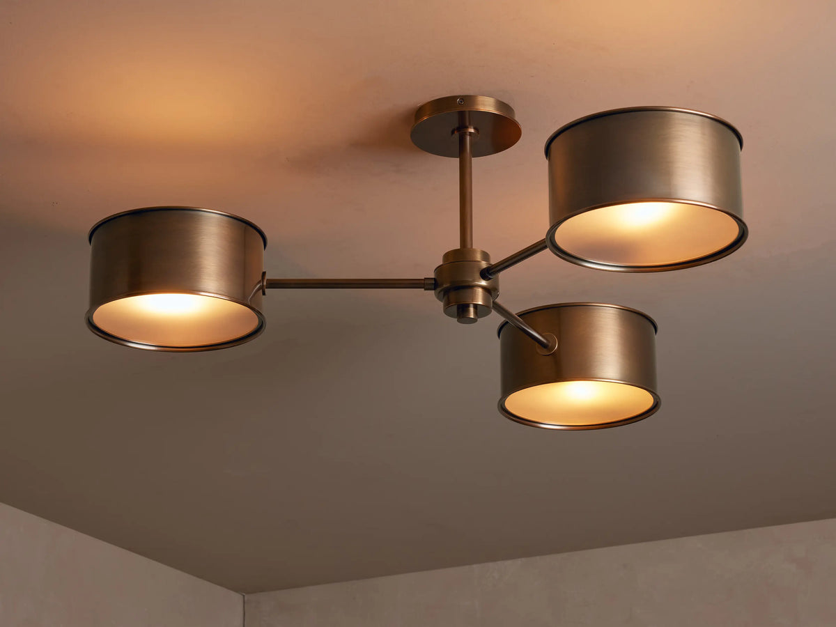 Close-up of a bronze Daphne Metal Flush Mount, featuring cylindrical shades emitting warm light onto a ceiling.