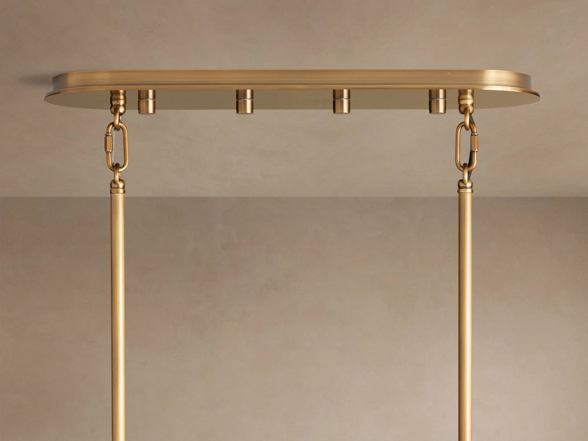 Close-up of Delsie Oval Tiered Chandelier; warm light glows through rows of fluted, textured glass rods & brass frame.