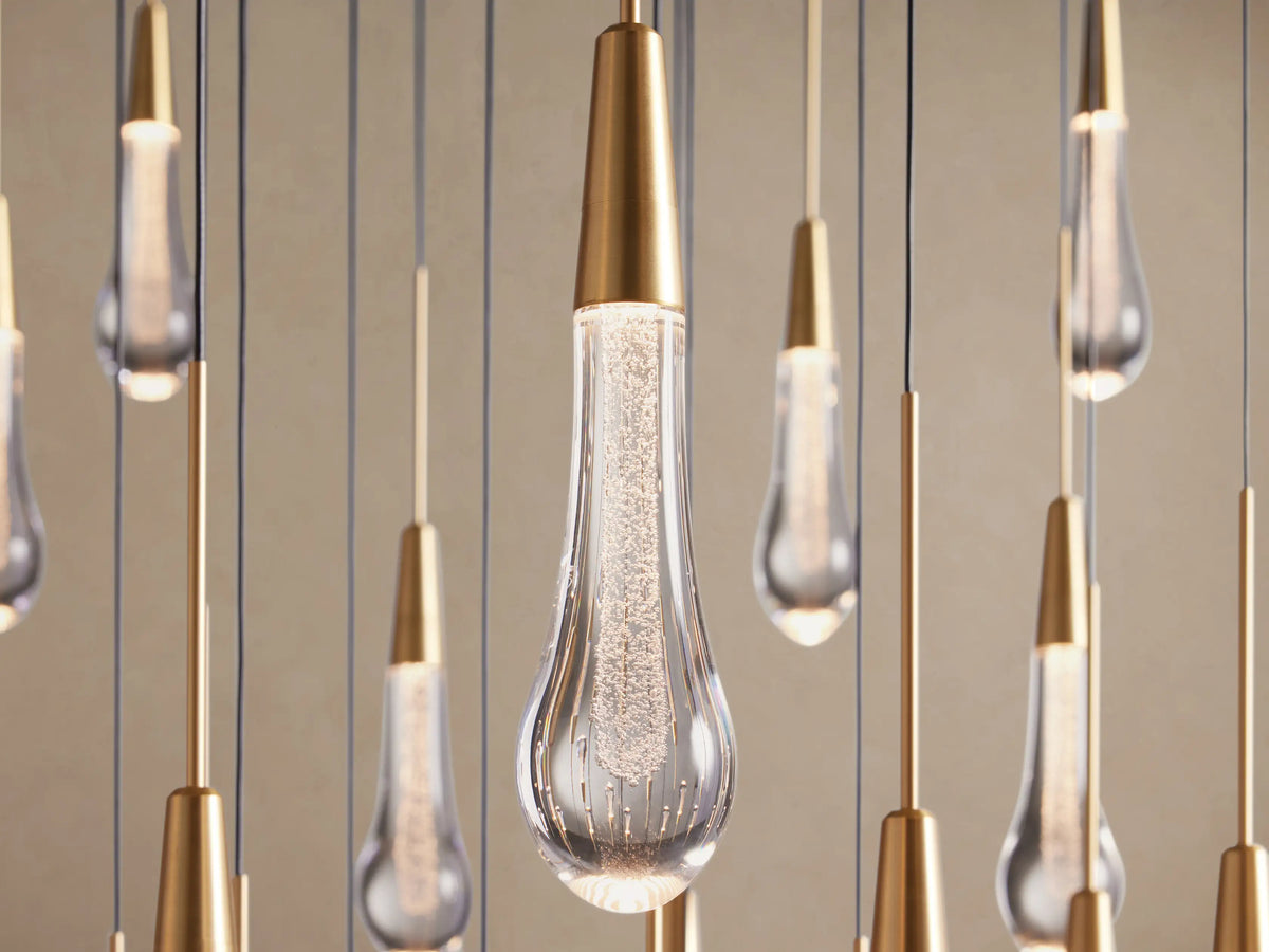 Close-up of Soltaire Round Chandelier with multiple clear teardrop glass lights, brass caps, and internal bubbly texture.