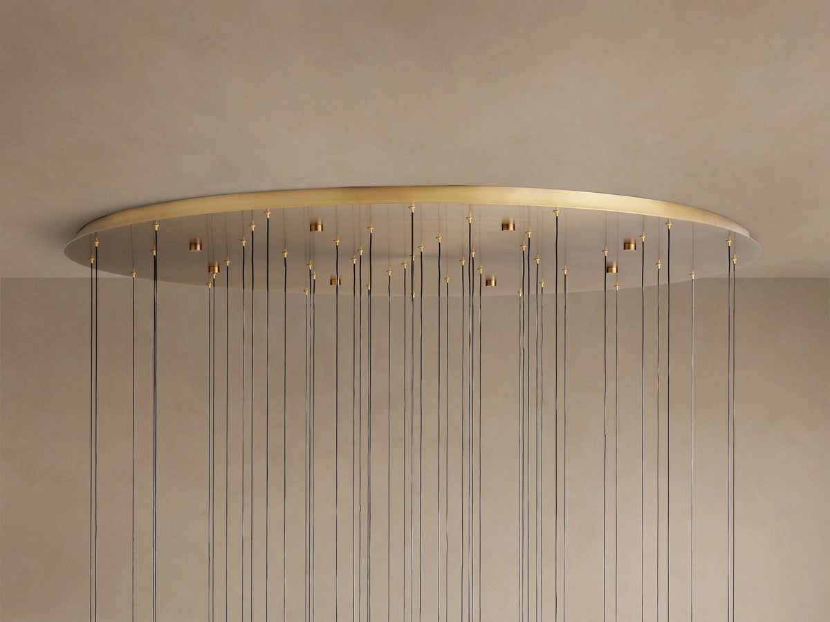 Soltaire Round Chandelier: large, round, golden brass ceiling plate mounted to a light ceiling, with numerous thin dark wires hanging down.