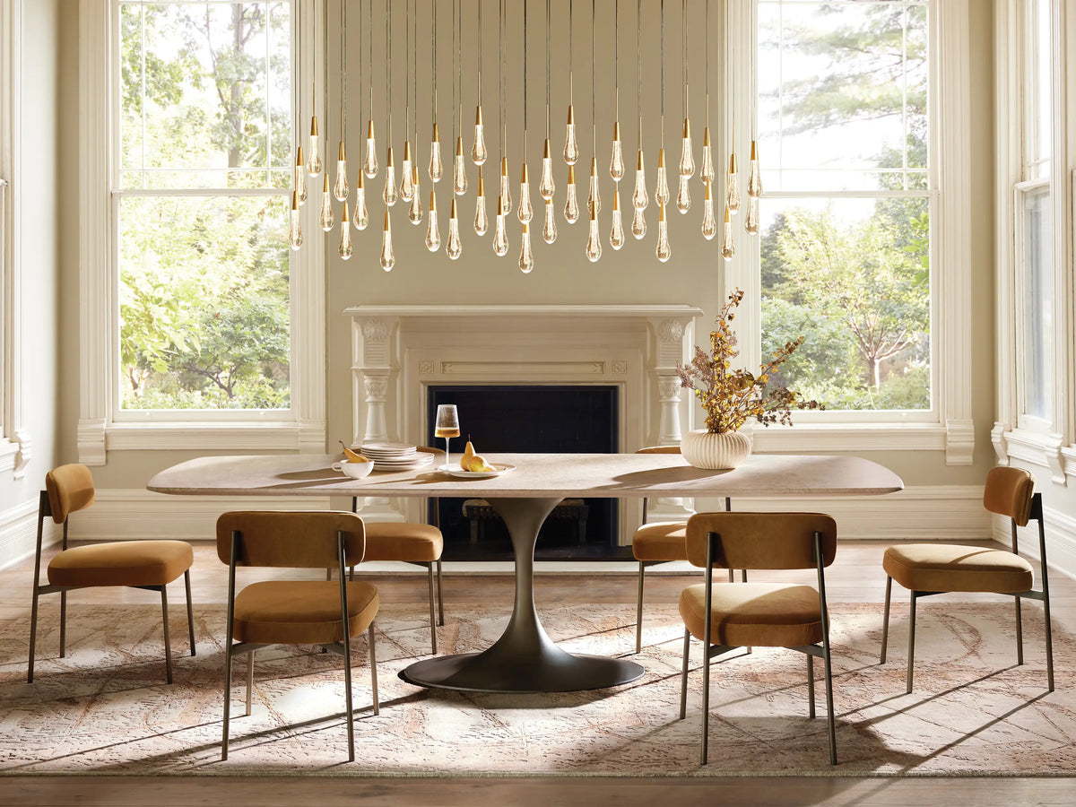 Soltaire Linear Chandelier with numerous illuminated clear glass teardrop lights, each with a brass-finished cap, hanging.