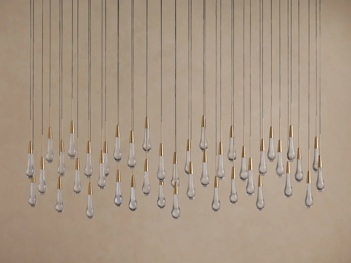 Linear Soltaire Chandelier with numerous clear glass teardrop bulbs, brass caps, hanging from thin wires at varied lengths.