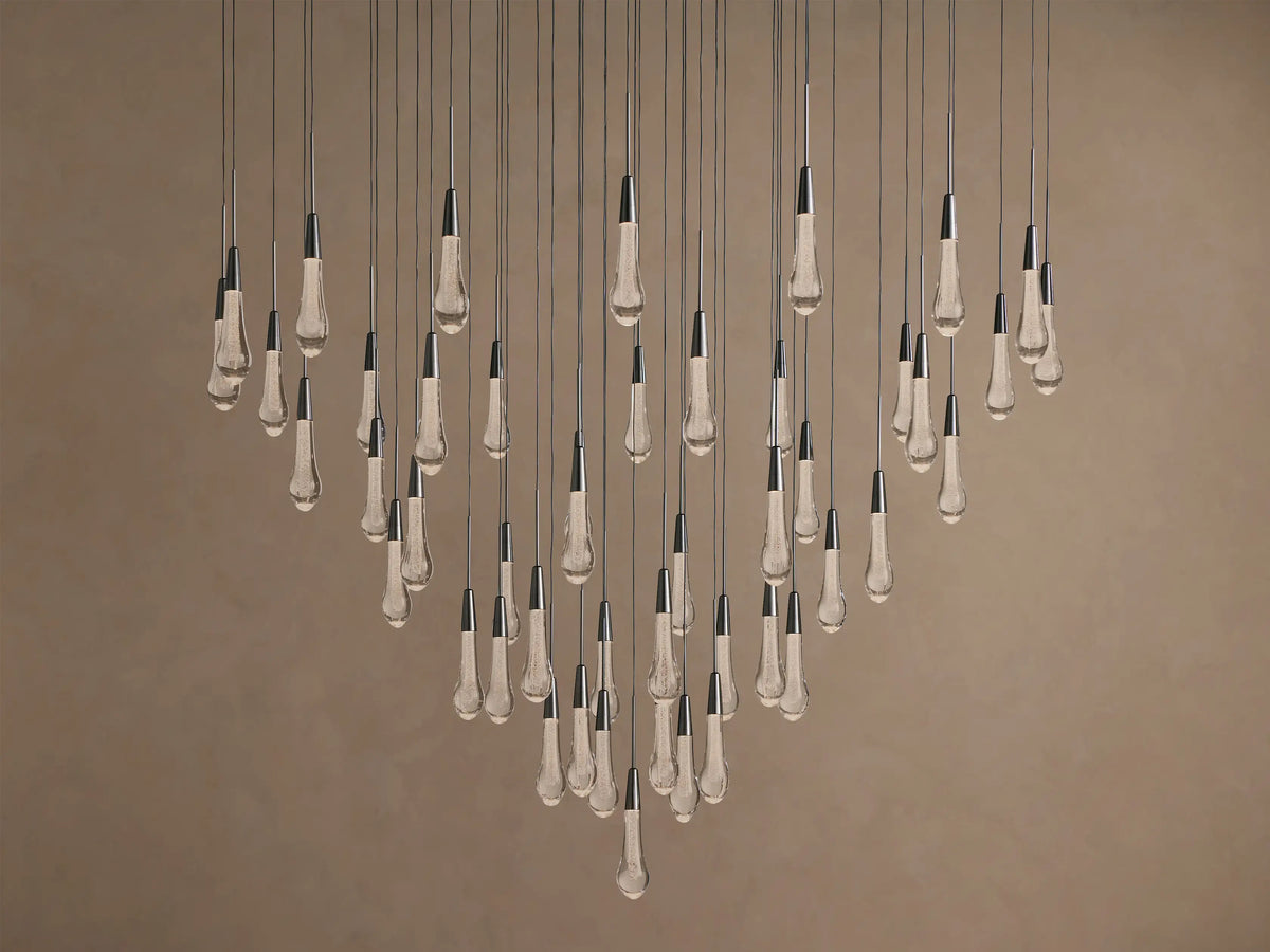 Soltaire Round Chandelier with multiple clear, textured, teardrop glass bulbs, dark metallic caps, suspended at varying lengths.