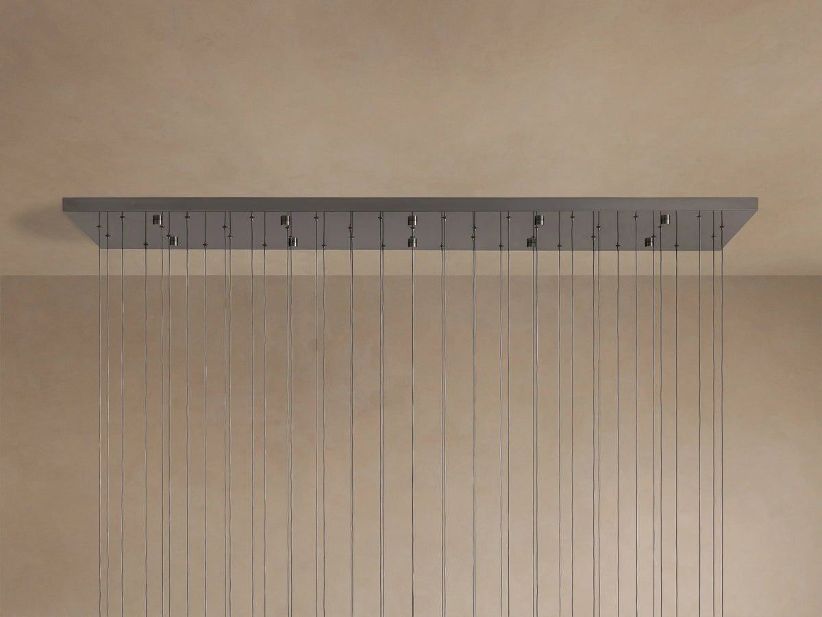 Soltaire Linear Chandelier: long rectangular metallic grey canopy with many evenly spaced thin wires hanging down from a ceiling.