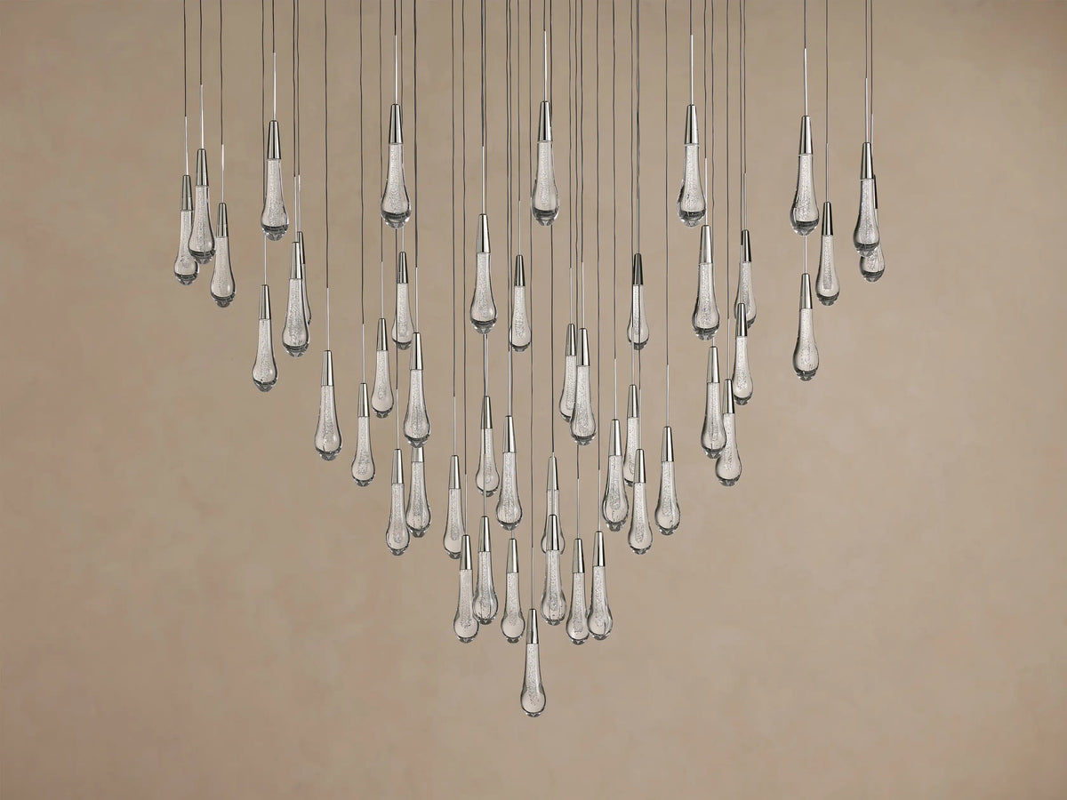 Soltaire Round Chandelier: Many clear glass teardrop pendants with silver-toned tops, suspended and emitting a warm glow.
