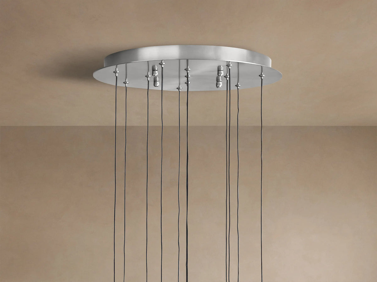 Close-up of Soltaire Round Chandelier with clear, teardrop glass pendants, internal bubbles, chrome accents, and warm glowing light.