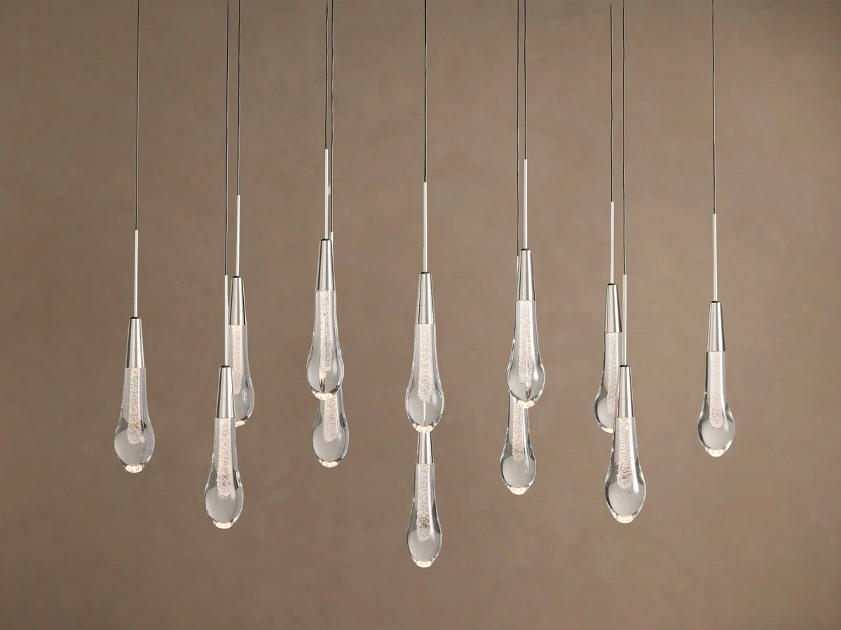 Soltaire Linear Chandelier with sparkling clear teardrop glass pendants, silver-finished tops, hanging at various lengths.