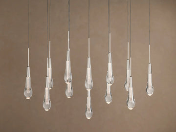 Soltaire Linear Chandelier with sparkling clear teardrop glass pendants, silver-finished tops, hanging at various lengths.