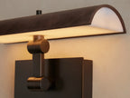 Abel Picture Light Sconce: dark brown leather-wrapped steel light and bronze backplate, mounted on a neutral wall above framed art.