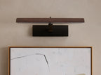 Abel Picture Light Sconce, dark brushed bronze, horizontally mounted over an abstract artwork, casting warm LED light.