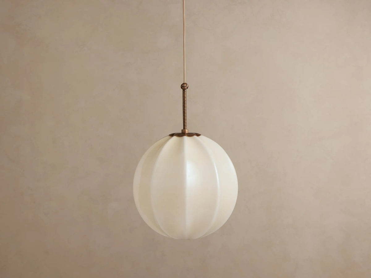 Agnes Pendant: Spherical, paneled cream glass shade glowing warmly, hanging from an antique brass rod & thin wire.