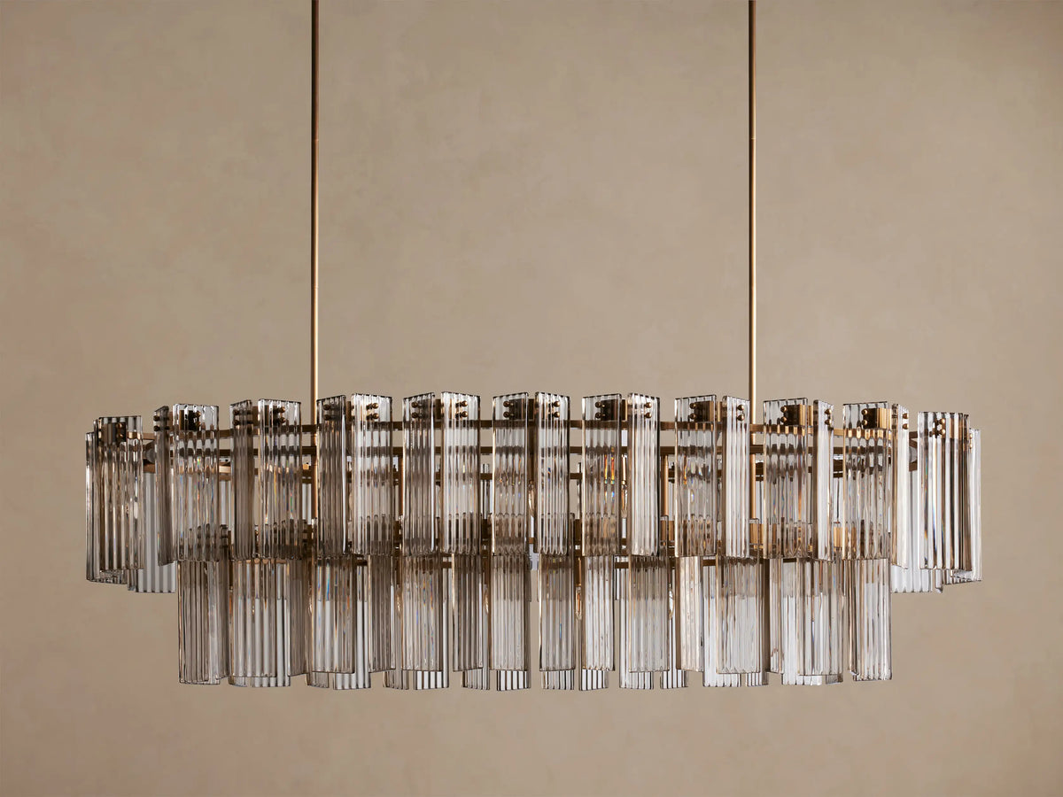 Delsie Oval Tiered Chandelier, hanging. Oval, two tiers of fluted clear glass rods on a burnished brass frame, lit from within.