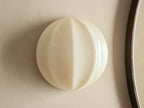 Agnes Clamshell Sconce: Spherical cream paneled glass sconce, glowing warmly, mounted on a light wall next to a dark mirror.